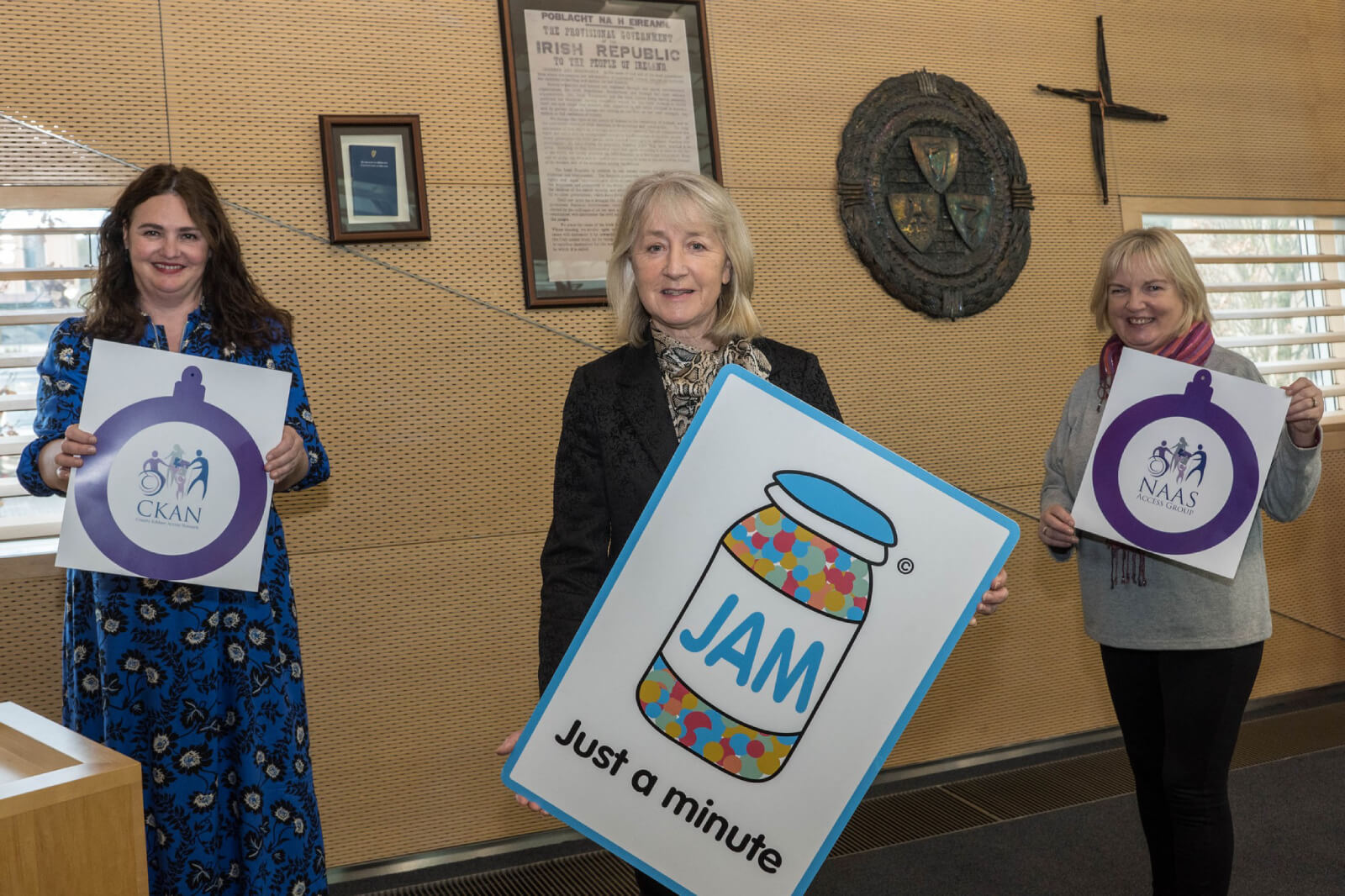 A group of women standing together holding CKAN , NAAS and JAM posters.